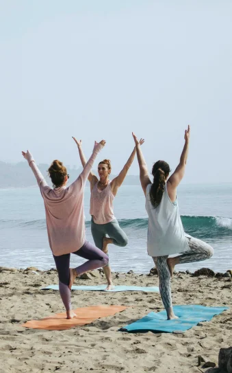 Tres chicas haciendo Yoga en la playa